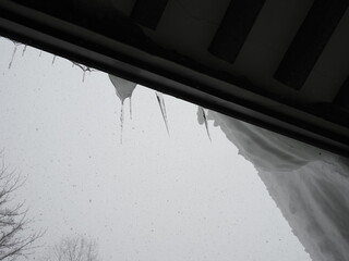 屋根にぶら下がる雪