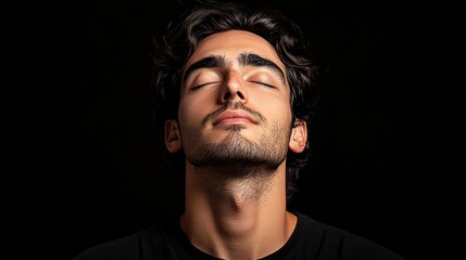 Fototapeta premium Serene Young Man Portrait: Peaceful Expression and Tranquil Mood in Close-Up Studio Shot