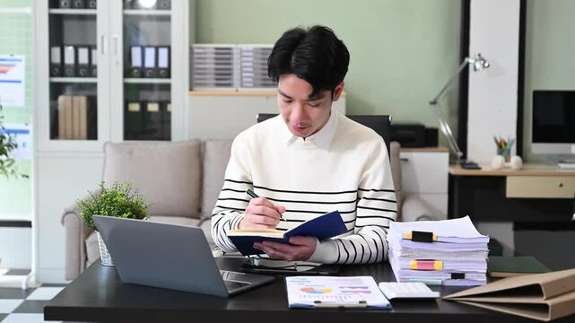 Young Businessman using laptop and tablet while sitting at her working place