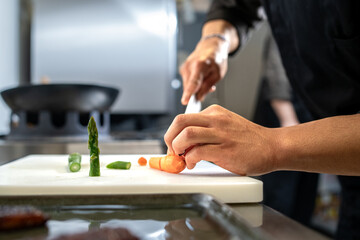 Chef slicing vegetables with knife on cutting board in kitchen preparation