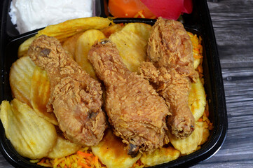 Broasted chicken meal with colorful Basmati rice, pickled slices of carrot, cucumber, turnip, fried potato chips, a broast chicken pieces, broasting combines pressure and traditional shallow frying