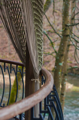 Close-up of a woven curtain tied to a wooden pole with river and forest backdrop. High quality photo