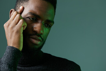 African american man in turtleneck sweater listening intently with hand to ear indoors