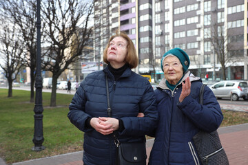 Two elderly ladies, mother and daughter, walking around the city, talking, laughing, drinking coffee. Active healthy lifestyle