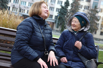 Two elderly ladies, mother and daughter, walking around the city, talking, laughing, drinking coffee. Active healthy lifestyle