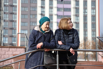 Two elderly ladies, mother and daughter, walking around the city, talking, laughing, drinking coffee. Active healthy lifestyle