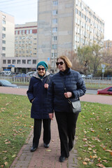 Two elderly ladies, mother and daughter, walking around the city, talking, laughing, drinking coffee. Active healthy lifestyle
