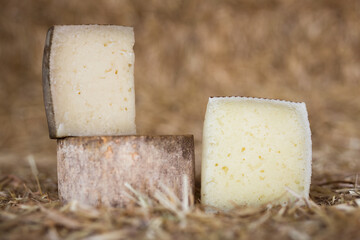 Whole head of ripe country cheese and slices on hay