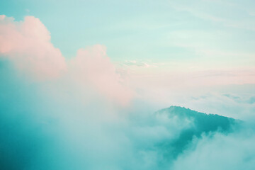 Naklejka premium Serene landscape of soft pastel clouds enveloping distant mountains during sunset, evoking tranquility