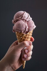 Hand holding an ice cream cone on gray color