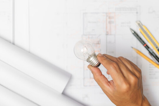 The architect holding light bulb on blueprint of the new home. energy saving for smart home. architecture for construction house building. architect studio.