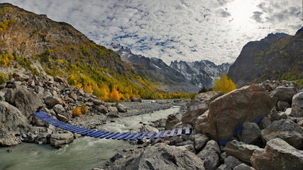 Russia. Kabardino-Balkaria. Panoramic view of the Shkhelda mountain river surrounded by the Caucasus Mountains with glaciers feeding the muddy river.