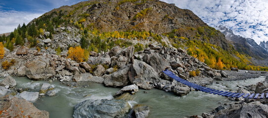 Russia. Kabardino-Balkaria. Panoramic view of the Shkhelda mountain river surrounded by the Caucasus Mountains with glaciers feeding the muddy river.