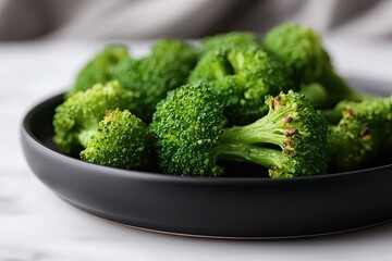 Freshly harvested broccoli arranged neatly on sleek black plate,