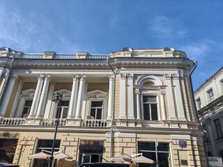 Fototapeta premium bright yellow facade with tall windows and a central archway entrance, adorned with classical decorative elements. This image captures the timeless beauty of classical architecture in a modern urban