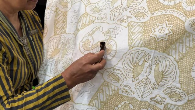 Asian woman painting Batik Tulis.