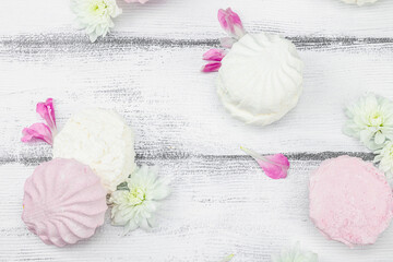 Fruit marshmallow with fresh flower petals on white wooden background. Lactose free vegan dessert