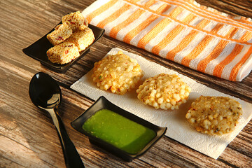 Tabletop shot of ""Sabudana Vada"" with green chutney and Rajgira Wadi, a popular snack or food eaten during fasting.