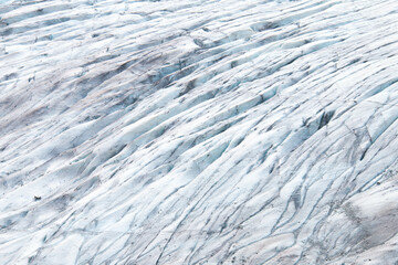 Detailed closeup of Glacier Surface showcasing intricate Ice textures and patterns. Icy landscape features subtle blue hues and dark streaks, the natural beauty and complexity of winter scene