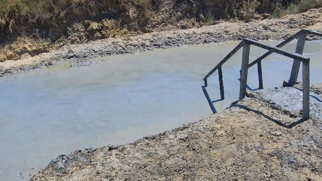Mud volcano Hephaestus. The Pool with volcanic mud and ladder to go down in Hephaestus. Therapeutic mud is for health improvement human body and used in cosmetology, baths. Horizontal video 4k.
