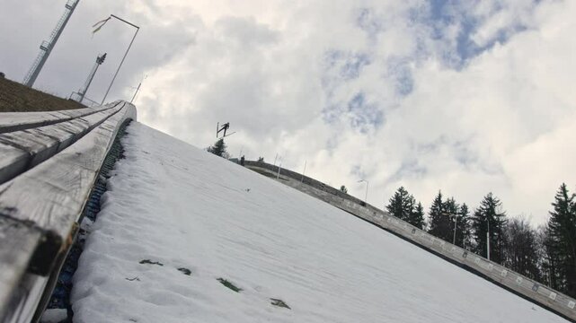 Professional male athlete performing ski jumping, flying through the air, and landing on a landing slope during training, low angle shot.