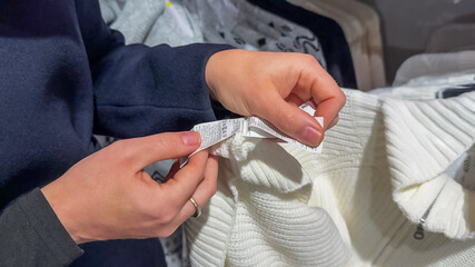 A person checks a clothing label in a store, highlighting conscious shopping choices and sustainability awareness in retail