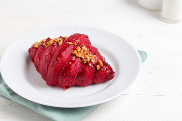 Red velvet croissant on a white plate.