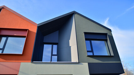 Terraced family homes in newly developed housing estate. The real estate market in the suburbs. New single family houses in a new development area. Residential homes with modern facade. 