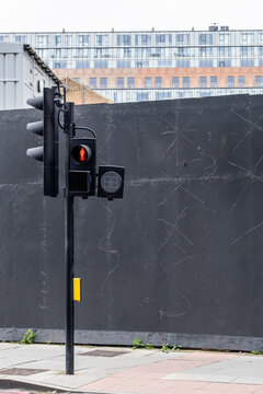 A traffic light signaling 'stop' stands in front of a stark black wall, revealing urban elements that capture the essence of city living and the flow of daily life.