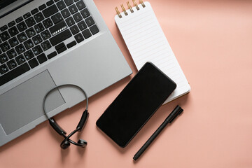 Workplace -  smartphone, notepad, laptop, headphones, pen on beige background. Top view with space for text