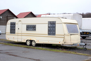 Old Classic Camper on wheels at the parking. White Travel Trailer at the city street. Five seater travel trailers parked in a city parking lot. Camping trailer. Moving house at the parking. Right view