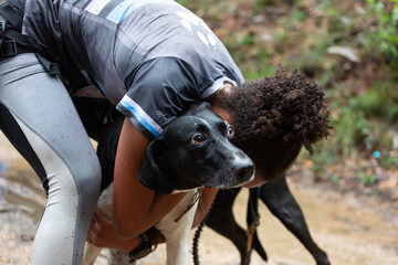 A mushing runner hugs her dog at the end of the race