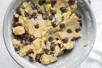 Overhead view of chocolate chip cookie dough, top view of homemade chocolate chip cookie dough in a bowl on a white background, process of making chocolate chip cookies