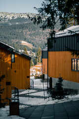 Mountain retreat with wooden cabins nestled in snow-covered landscape during winter afternoon