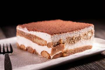 Tiramisu cake dessert served with coffee, biscuit and cocoa on dark background.spoon. Dessert. Food Concept