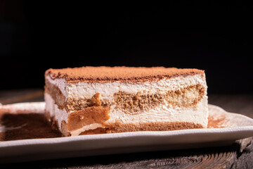 Tiramisu cake dessert served with coffee, biscuit and cocoa on dark background.spoon. Dessert. Food Concept