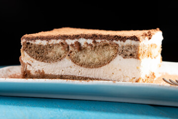 Tiramisu cake dessert served with coffee, biscuit and cocoa on dark background.spoon. Dessert. Food Concept