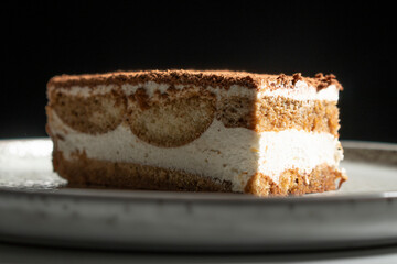 Tiramisu cake dessert served with coffee, biscuit and cocoa on dark background.spoon. Dessert. Food Concept