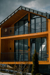 Modern wooden cabin with large windows in snowy landscape during winter afternoon