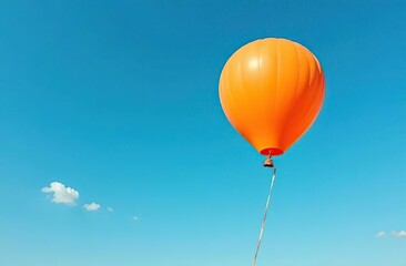 Obraz premium An orange balloon drifts against a vibrant blue sky, symbolizing joy, freedom, and the lightness of being