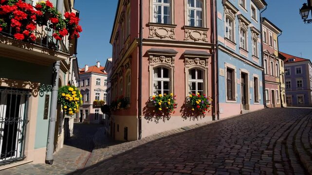 A picturesque cobblestone street in a historic European town, lined with colorful facades and blooming flowers in window boxes.