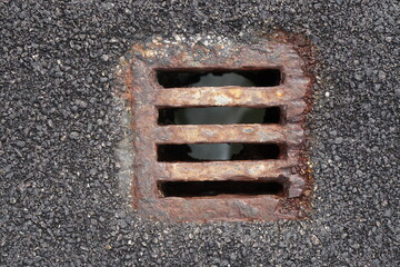 rusty iron manhole on asphalt