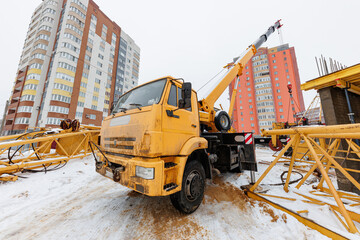 Amidst Winters Chill, A Yellow Crane Stands Tall Building Dreams in a Snowy Urban Landscape.