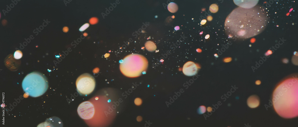 Poster colorful confetti particles floating in a dark space with a focus on gold highlights
