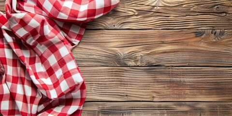 Obraz premium Cloth napkin at empty wooden background top view. Checkered red tablecloth placed on the side of old wood brown table surface. Copy space. Kitchen blank counter. Free space for product and information