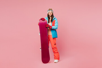 Full body young smiling happy cheerful woman she wear warm blue padded jacket ski goggles mask...