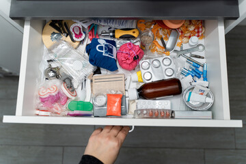 hand opening a drawer full of various objects piled up in a pile