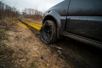 Close-up view of wheels with all-terrain tires. Off-road vehicle with 4-wheel drive. Mud stuck to the tread. Slippery ground after rain. Nature and travel