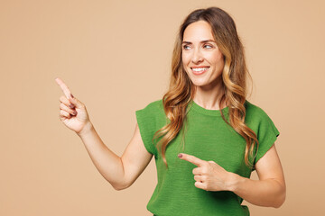 Young smiling happy woman she wear green t-shirt casual clothes point index finger aside indicate...