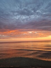 Serene ocean or sea at sunset, gentle waves, vibrant hues of orange, pink, and purple, dramatic sky, sense of romance, slowing down, tranquility, meditation, peacefulness